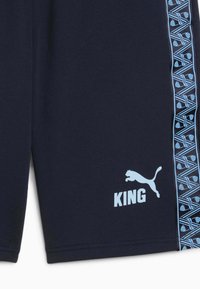 Marineblå athletic shorts med et lyseblåt mønstret sidelæbe. Har "KING" i lyseblå tekst og et matchende logo. Lavet af fleksibelt materiale.