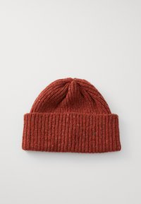 Bonnet en laine tricoté couleur rouille avec revers, posé à plat sur une surface blanche.