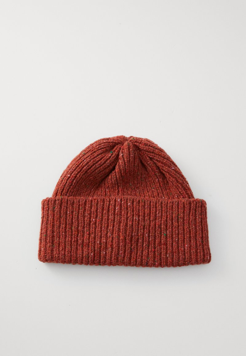 Bonnet en laine tricoté couleur rouille avec revers, posé à plat sur une surface blanche.