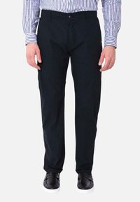 Pantaloni navy in cotone con taglio dritto, dotati di chiusura con bottone, tasche laterali e abbinati a scarpe slip-on nere.