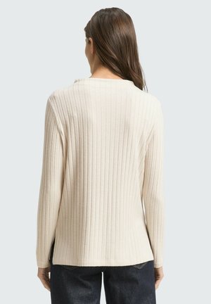 Pull en crème côtelé à manches longues, avec fentes sur les côtés et un col rond, fabriqué à partir d'un tissu tricoté doux. Vue de dos montrée.