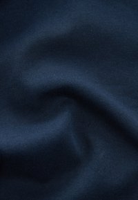 Tissu bleu marine avec une texture lisse, présentant une légère élasticité et un fin côtelé, montrant des plis doux et une brillance subtile.