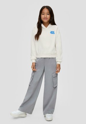 Witte hoodie met blauwe tekst "lost vibes", gecombineerd met losse grijze cargobroeken met grote zijzakken en witte sneakers.