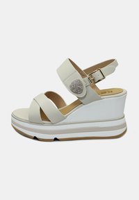 Witte wedge sandalen met een kruisbandontwerp, verstelbare enkelband, glad leren materiaal en een decoratieve strassaccent op de band.
