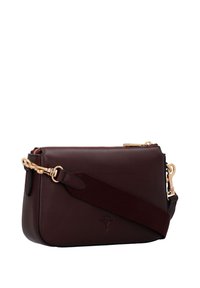 Bordó kožená kabelka přes rameno se zlatými detaily, odnímatelným textilním popruhem a embosovaným logem na přední straně. Zipové uzavírání nahoře.