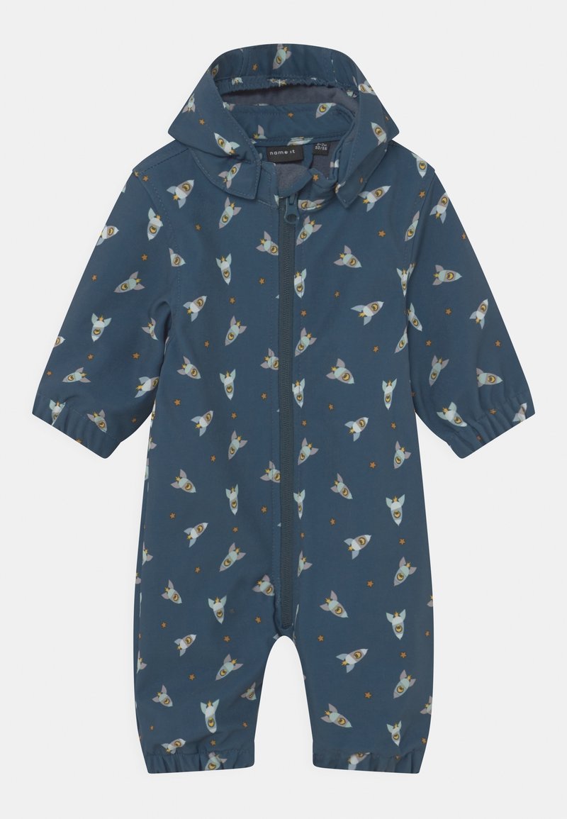Combinaison de pluie bleu foncé avec motif de fusée et d'étoiles, fermeture éclair et manches courtes. Confectionnée en matériau résistant à l'eau, design léger.