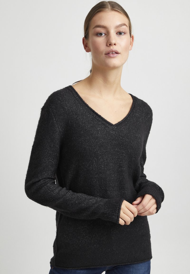 Pull noir à manches longues avec un design en V, motif en maille texturé et coupe légèrement ample. Détails de bord-côtes aux poignets et à l'ourlet.