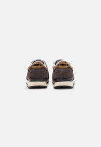 Zapatillas de ante marrón con acentos negros, parte superior de malla blanca, talón contrastante y detalle de logo. Presentan una suela acolchada para mayor comodidad.