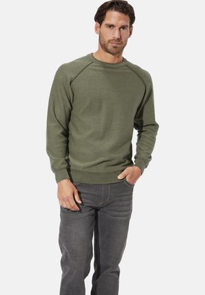 Olivegrüner Sweatshirt mit Rundhalsausschnitt, gerippten Bündchen und Bündchen, mit glatter Textur. Getragen zu grauen Jeans.