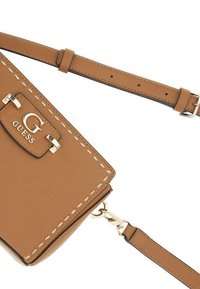 Sac en simili cuir marron à bandoulière avec quincaillerie dorée, présentant un logo G proéminent et des détails de surpiqûre contrastants. Sangle réglable incluse.