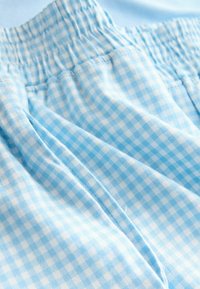 Tela a cuadros de gingham en azul claro con una cinturilla elástica, que presenta una textura suave y un acabado sutilmente suave.