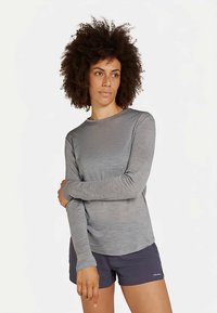 Grijze longsleeve gemaakt van lichtgewicht, gestructureerde stof met een ronde hals, gecombineerd met donkere korte broek. Minimalistisch ontwerp zonder opvallende patronen.