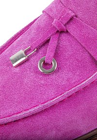 Chaussure en daim rose avec une texture lisse, dotée d'un accent métallique décoratif et d'un oeillet circulaire pour les lacets. Design à bout rond.