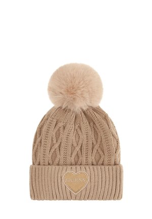 Bonnet en tricot beige avec un revers côtelé, surmonté d'un pompon en fausse fourrure et d'une étiquette en cuir en forme de cœur embossée avec "GUESS".