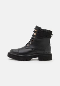 Stivale nero in pelle alla caviglia con un motivo in croco a tessuto sulla punta, colletto foderato in pelliccia, accessori in oro rosa e suola spessa.