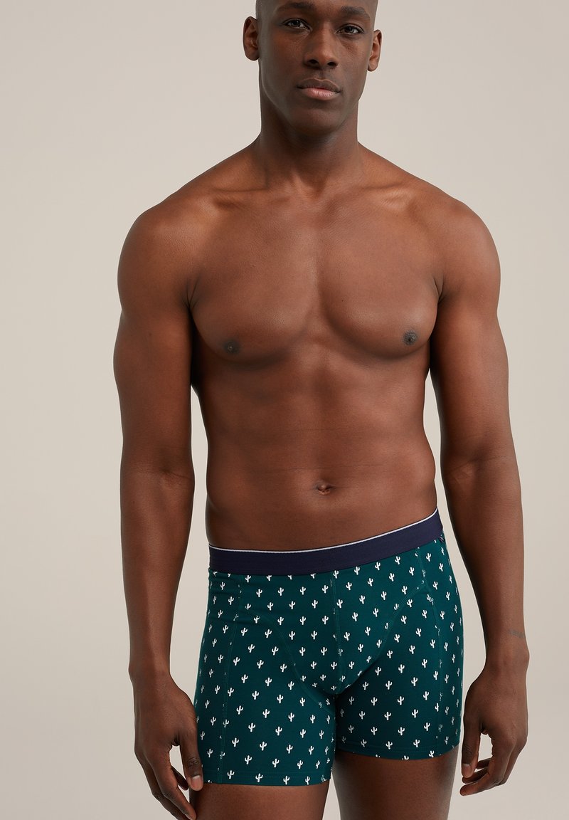 Sötétzöld férfi boxeralsó, fehér kaktusz mintával. Sötétkék rugalmas derékpánttal készült. Puha, rugalmas anyagból készült.
