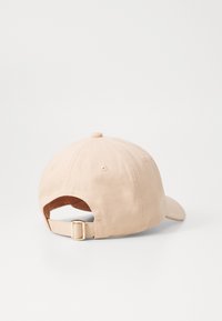 Beige színű pamut sapka ívelt karimával, hátul állítható pánttal és sima felülettel. Hat szellőzőnyílással és felső gombbal rendelkezik.