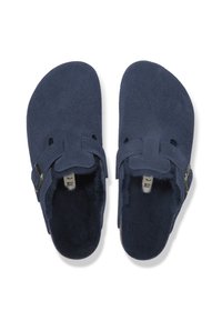 Dunkelblaue Wildlederclogs mit flachem Design, ausgestattet mit zwei Riemen und metallischen Akzenten. Weiche Fellbespannung im Innenraum für zusätzlichen Komfort.