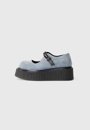 Lyseblå denim Mary Jane sko med sort spænde og tyk struktureret sort platformsål, vist i sideprofil på hvid baggrund.