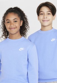 Lys blå hettegensere med rund hals; ribbede mansjetter og hemper; har hvit Nike-logo på venstre bryst; glatt bomullsstoff.