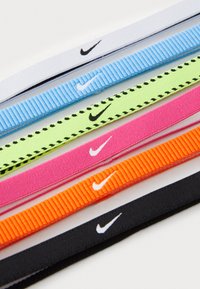 Nike elastische haarbanden in zes kleuren: wit, lichtblauw, neon groen met zwarte stippen, roze, oranje en zwart. Elke haarband heeft een Nike-logo.
