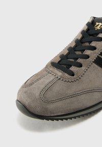 Graue Wildledersneaker mit schwarzen Schnürsenkeln, strukturiertem Obermaterial und runder Zehenform. Verfügt über dezente Nähte und eine schwarze Gummisohle mit Profil.