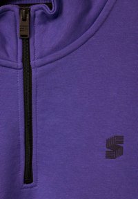 Purple zip-up sweatshirt with a high collar, featuring a black zipper and a black logo on the chest. Smooth texture, casual fit.