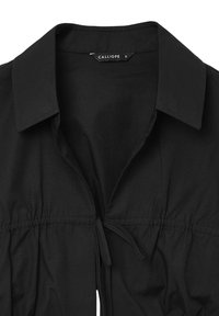 Blusa nera con colletto, caratterizzata da una vita arricciata con lacci regolabili, realizzata in tessuto liscio e con dettagli di design minimalisti.