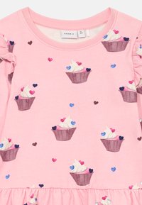 Rožinė ilgomis rankovėmis kūdikių suknelė su cupcake ir mėlynomis, rožinėmis bei violetinėmis širdelėmis, apvali iškirptė ir volanai ant rankovių bei apvalkalo.