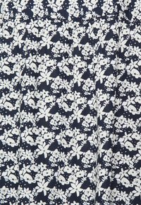 Tecido azul-marinho com um padrão floral branco apresentando várias flores e folhas. O material parece leve com um acabamento texturizado.