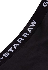 Črne bombažne spodnje hlače z širokim elastikastim pasom, na katerem je v belo napisan "G-Star RAW". Gladka tekstura in prilegajoča zasnova.
