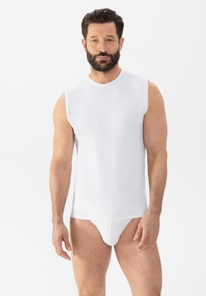T-shirt sans manches blanc en tissu lisse, avec un col rond et une coupe ajustée, associé à un slip blanc.