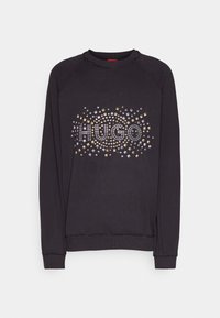 Sudadera negra de manga larga, con un diseño gráfico "HUGO" hecho de tachuelas metálicas de varios colores en el frente.
