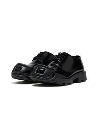 Chaussures en cuir verni noir avec un bout arrondi, présentant une découpe carrée distincte à l'avant et des semelles en caoutchouc texturé épaisses.