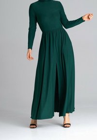 Langes, dunkelgrünes Kleid mit hohem Ausschnitt, langen Ärmeln und geraffter Taille. Verfügt über einen Vorder-Schlitz und einen fließenden Rock. Glatte Textur.