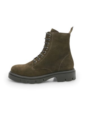 Bota corta de ante marrón con punta redondeada, ojales de metal, cordones en la parte delantera y una suela de goma negra texturizada. Detalles de costura distintivos en toda la bota.