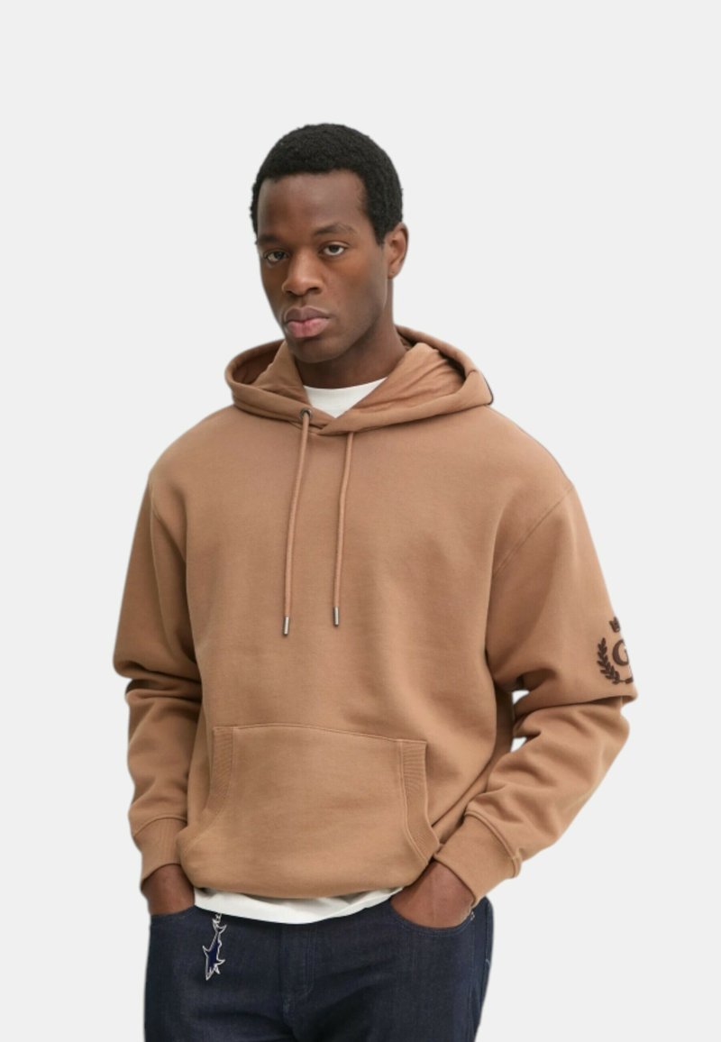 Felpa marrone con cappuccio e coulisse, tasca frontale e logo sul maniche. Realizzata in tessuto morbido con una trama liscia.