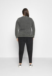 Šedá mikina z měkké látky, s žebrovaným límečkem a manžetami, v kombinaci s černými džíny. Bílé tenisky s černými akcenty dokončují vzhled.