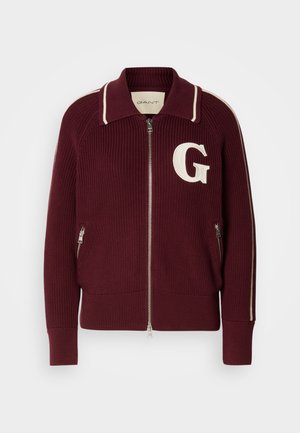 Maroon knitted zip-up sweater with white stripes on collar and sleeves, front zipper pockets, and large white "G" on left chest.