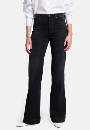Zwart flared jeans met een hoge taille, gemaakt van denim. Soepele textuur, subtiele stiksels. Gecombineerd met puntige witte hakken.