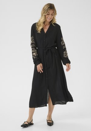Black long-sleeve dress with a button front, fabric tie waist, and gold embroidered details on sleeves. Smooth, slightly textured material.