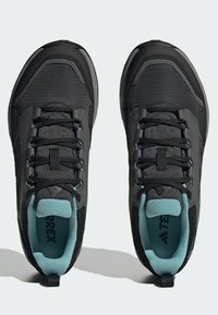 Zapatos de senderismo negros con parte superior de malla, suela de goma y acentos en teal. Las características incluyen cordones duraderos, cuello acolchado y logo en la lengüeta.