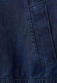 Tissu en denim bleu foncé avec une poche rectangulaire verticale et des fronces près du bord inférieur.