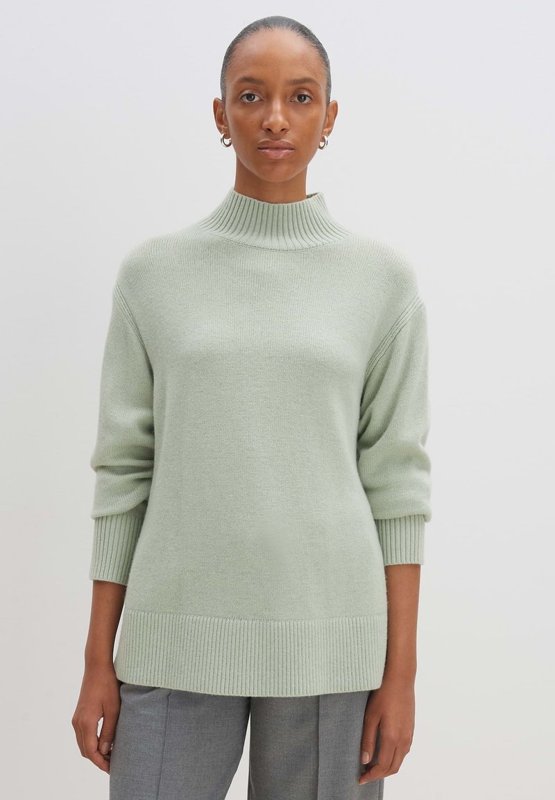 Hellgrüner, gestrickter Pullover mit hohem Kragen, Rippbündchen und Saum. Hat einen lässigen Schnitt und eine glatte Textur.