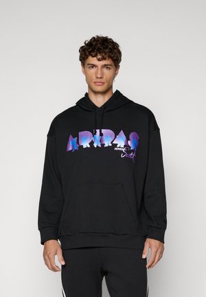 Črna kapuca z velikim, barvnim grafičnim napisem "ADIDAS" v vijolični in modri barvi. Ima sprednji žep in kapuco z vrvico.