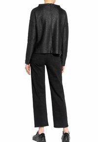 Top negro texturizado con un diseño corto y mangas cortas, combinado con pantalones negros de corte holgado. Ambas prendas presentan un diseño minimalista.