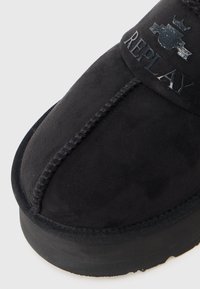 Cizmă neagră din suede la glezna, cu vârf rotund, talpă din cauciuc de profil redus și logo-ul „REPLAY” embosat pe lateral. Include cusături contrastante.
