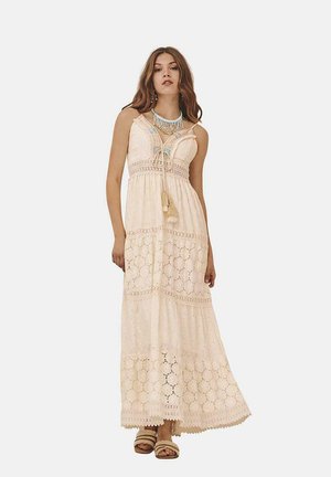 Vestido maxi en tejido beige claro, con detallado de encaje, tirantes ajustables, cintura con cordón y un diseño de falda en capas.