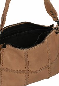 Bruine leren tas met gestikte details, ritssluiting en een zwarte binnenkant. Het handvat heeft een gevlochten ontwerp en metalen accenten.