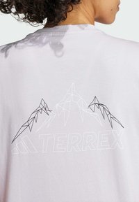 Světle šedé tričko s geometrickým grafickým motivem hory v černé a bílé barvě, s nápisem "TERREX" uvedeným níže tučným písmem.